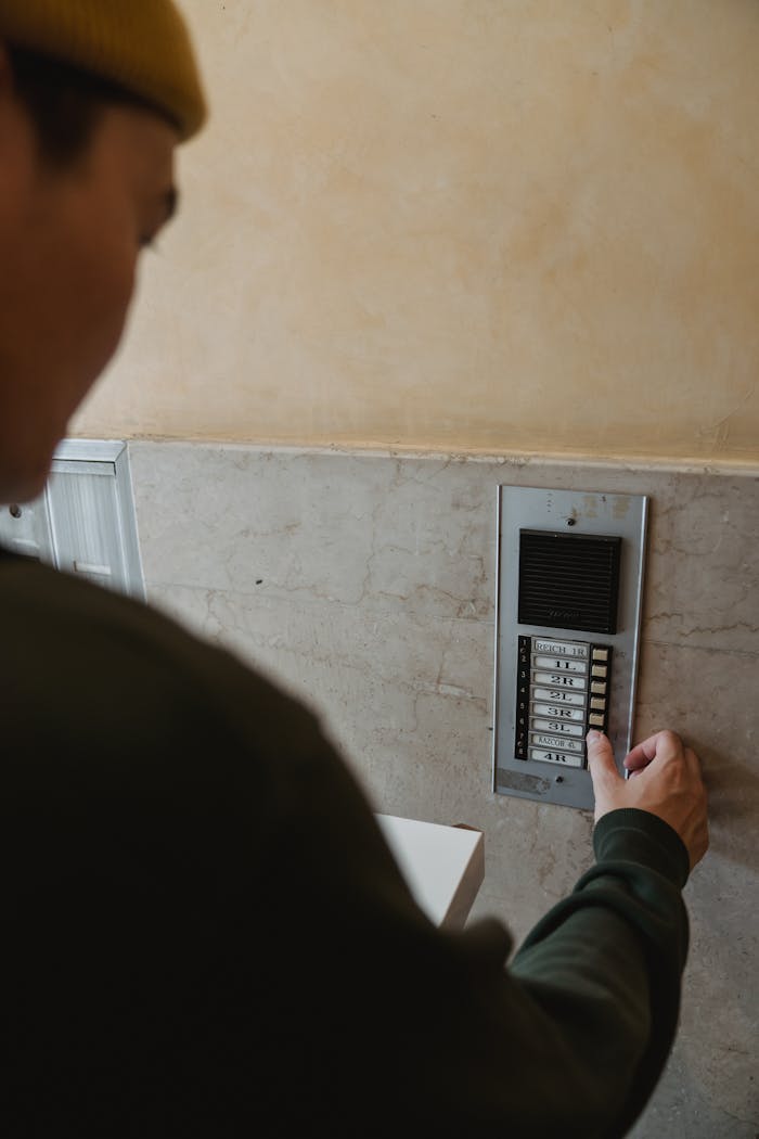 A person interacting with an intercom system in a building entryway for security purposes.